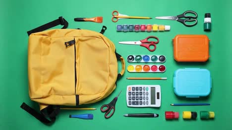 bright yellow backpack lying on a plain green background for a minimalist look