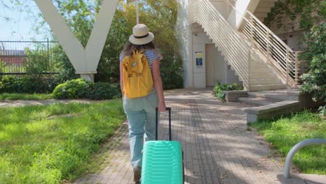 female tourist with backpack and suitcase in sunny park