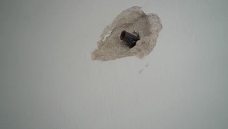 a cut black pipe protrudes from the wall, old wall with a protruding pipe, hole in the wall