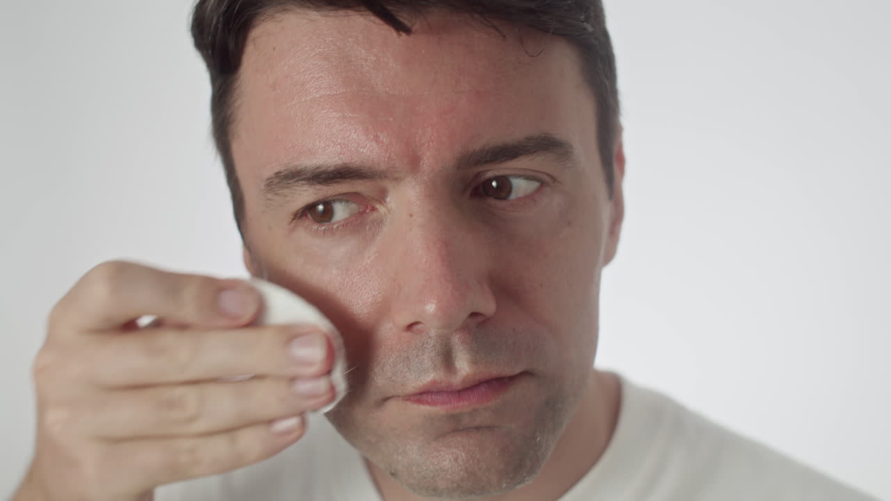 Gen Y Man Cleansing Skin with Micellar Water Applied on Cotton Pads