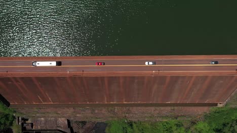 dam or dike seen from above with a road through which several vehicles pass next to a reservoir in misiones, argentina. drone perspective.