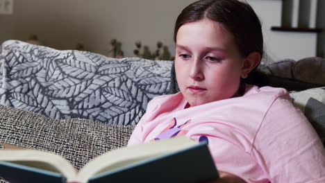 young girl reading book in living room