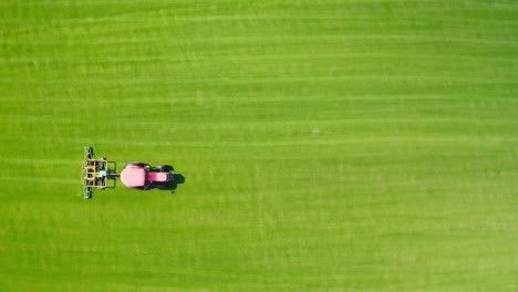 Roter-Traktor-Schneidet-Gras-Auf-Grünem-Feld-Und-Bewegt-Sich-Von-Links-Nach-Rechts