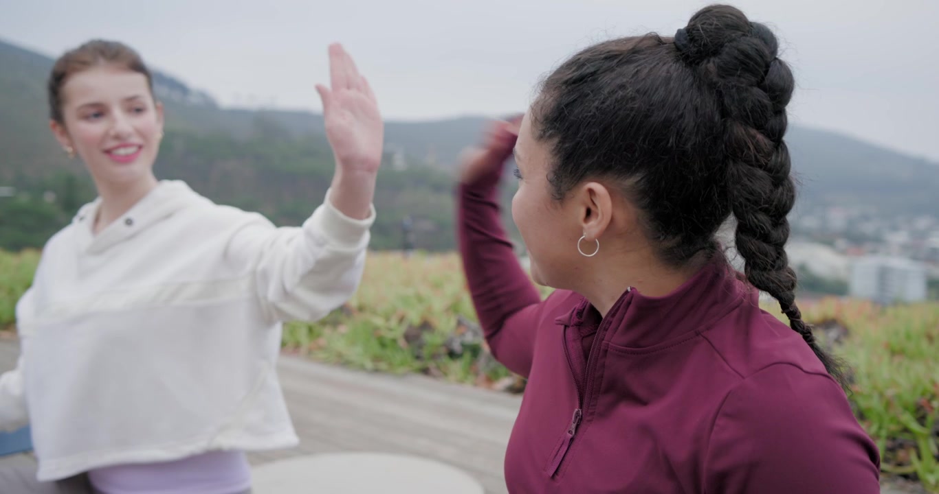 Diverse women sitting on yoga mats on deck during group meditation, burgundy woman opening eyes