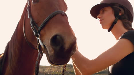 pretty woman putting on reigns on a horse