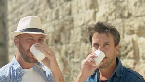 side view of happy gay couple drinking coffee outdoors