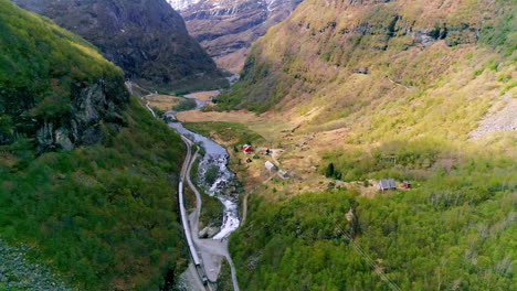 Long-train-driving-in-the-Viking-Valley-between-the-autumn-colored-mountain-sides-next-to-a-waterfall
