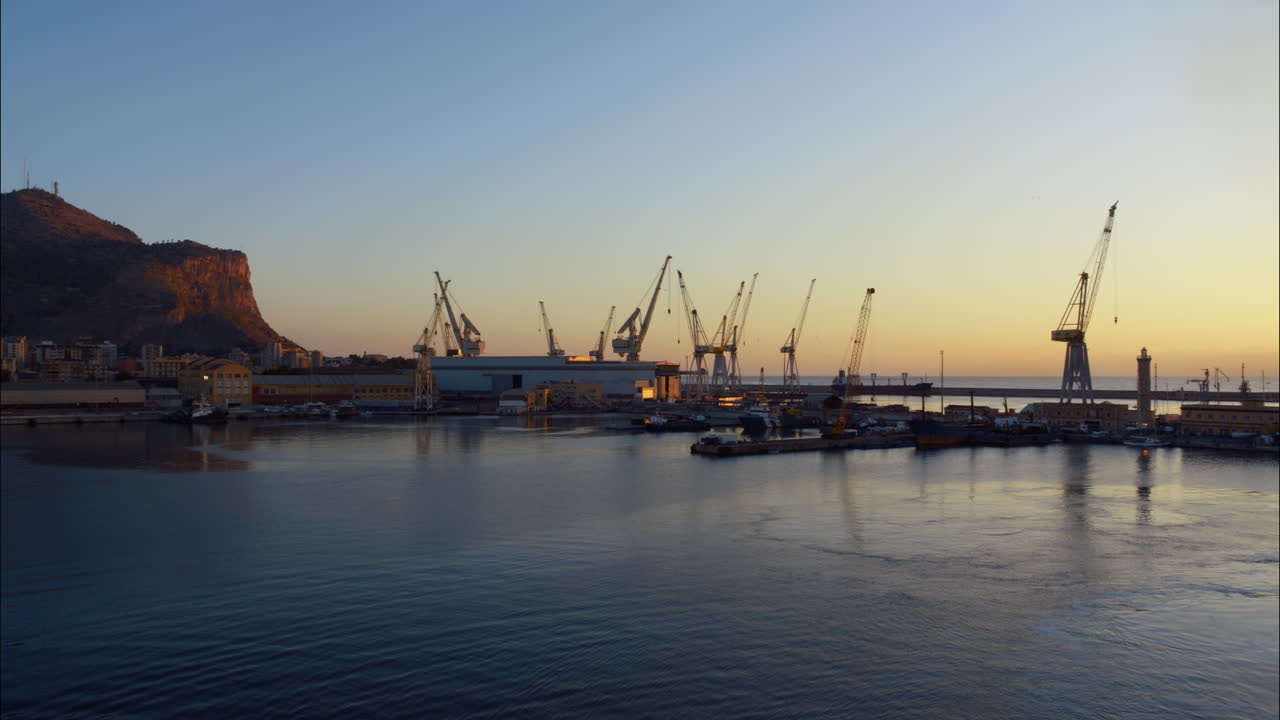 Sunrise over an Industrial Harbor with Cranes and Mountain