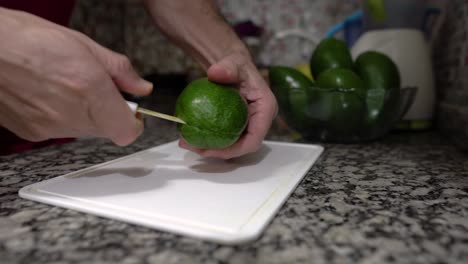 meal preparation: hands of a man cut fresh avocado on chopping board