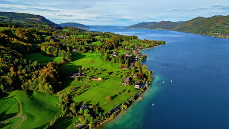 autumn at a village with a view of attersee lake, austria - aerial reveal