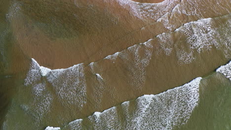 aerial top-down view of breaking waves on a beach