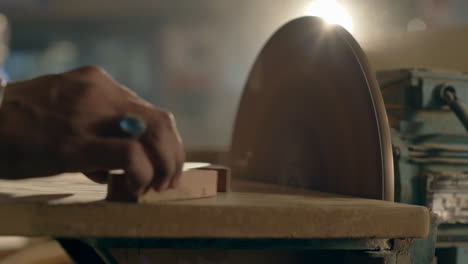 closeup of furniture maker sanding wood on a electric disc sander machine, manufacturing industry