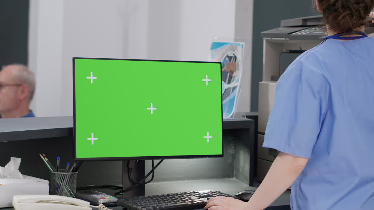 Medical staff working at hospital reception with green screen computer