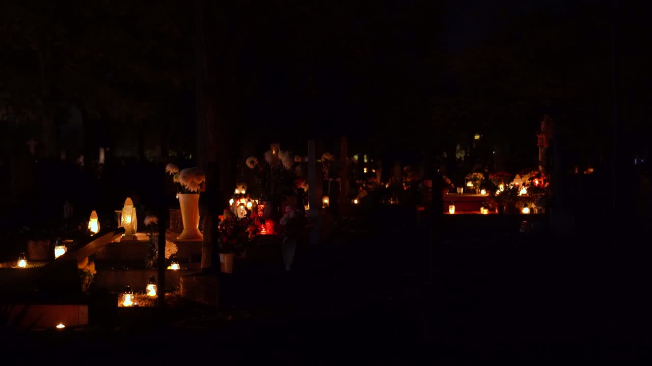 Graveyard illuminated with many flickering candles and fresh flowers commemorating deceased souls