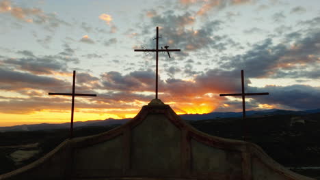 silhouette of three christian religious crosses in front of a sunset sky symbol