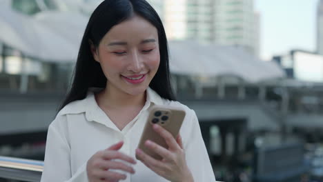 asian woman takes selfie and uses smartphone in city