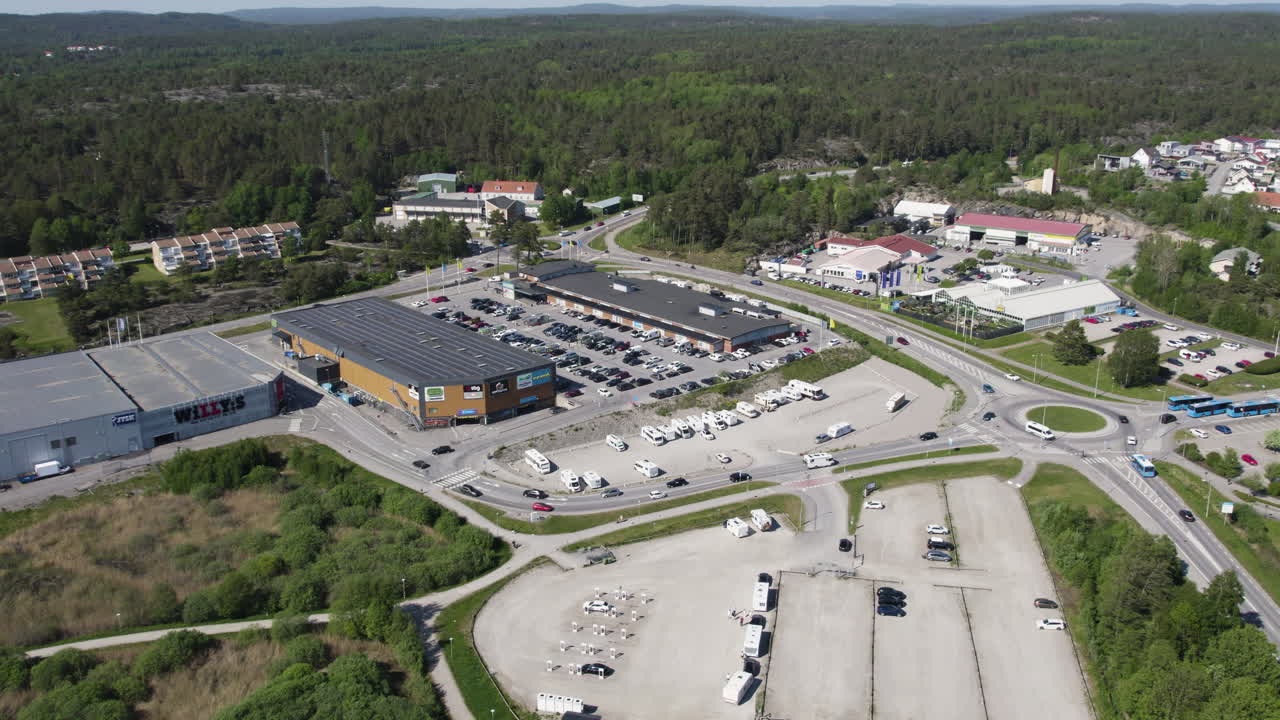 Aerial View of a Suburban Shopping Center with Large Parking Lots and Surrounding Greenery