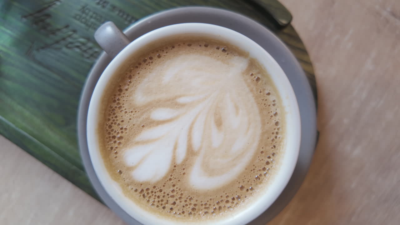 Close up big cup of cappuccino with coffee drawing art on top