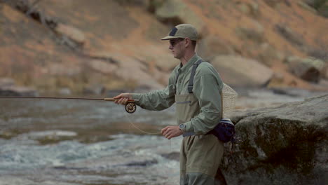 Cinematic-depth-of-field-Colorado-river-fly-fish-fisherman-with-waders-using-rod-fishing-in-water-Cheesman-Canyon-Deckers-Conifer-Evergreen-late-winter-early-spring-shaded-mountainside-still-movement