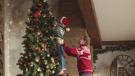 feliz padre e hija decorando el árbol de navidad en casa