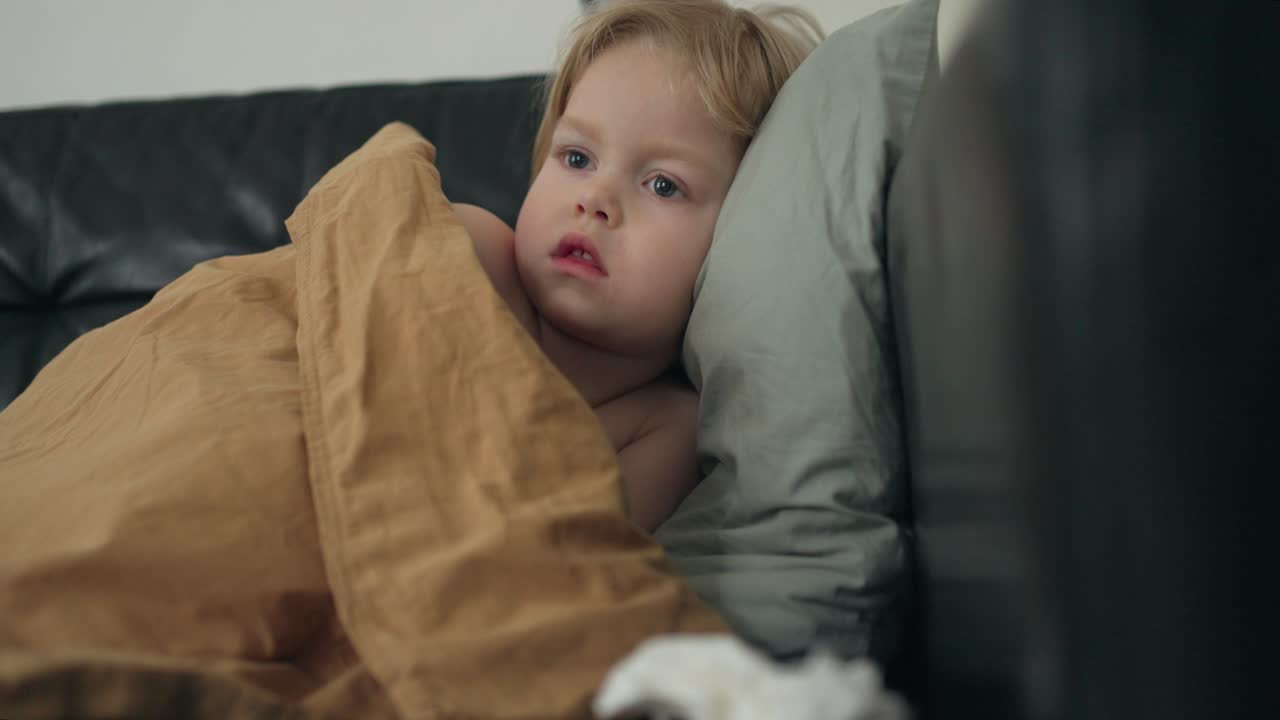 3살의 백인 소년, 검은색 소파에 담요로 싸여, 안심하는 휴식의 순간
