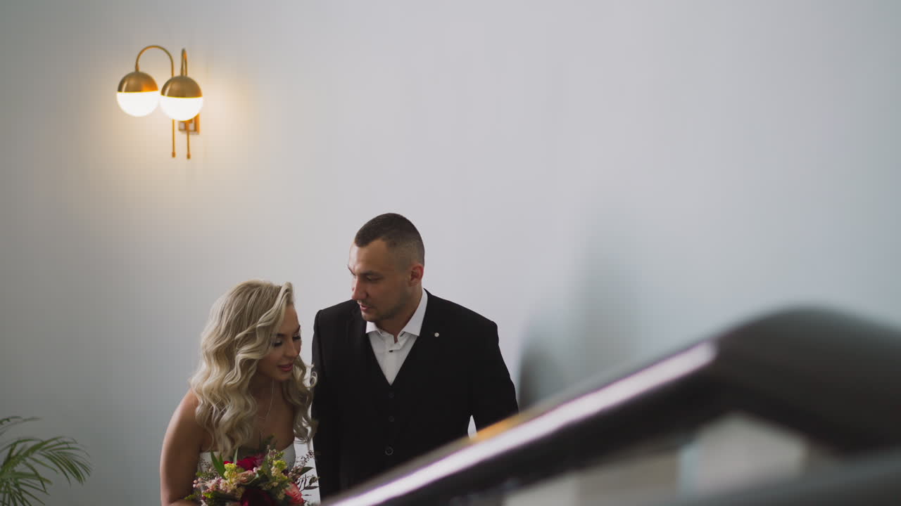 Una alegre pareja de recién casados sube las escaleras en un hotel.