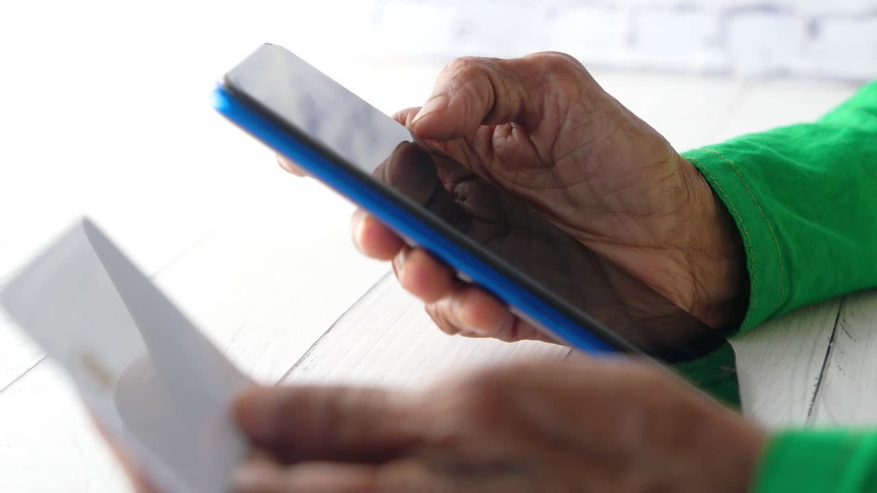 persona mayor usando un teléfono inteligente y documentos en una mesa