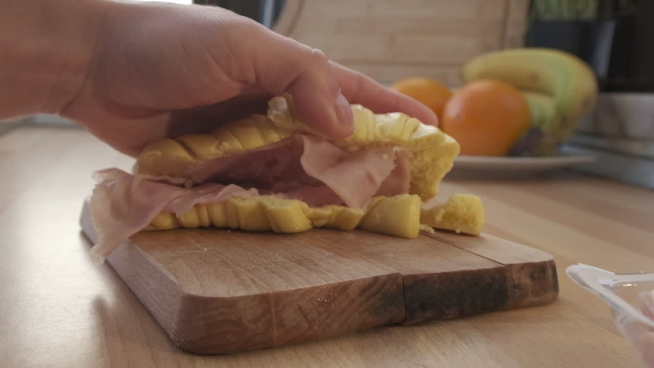 sándwich de croissant de jamón en una tabla de madera en la cocina - dolly in, cámara extremadamente lenta