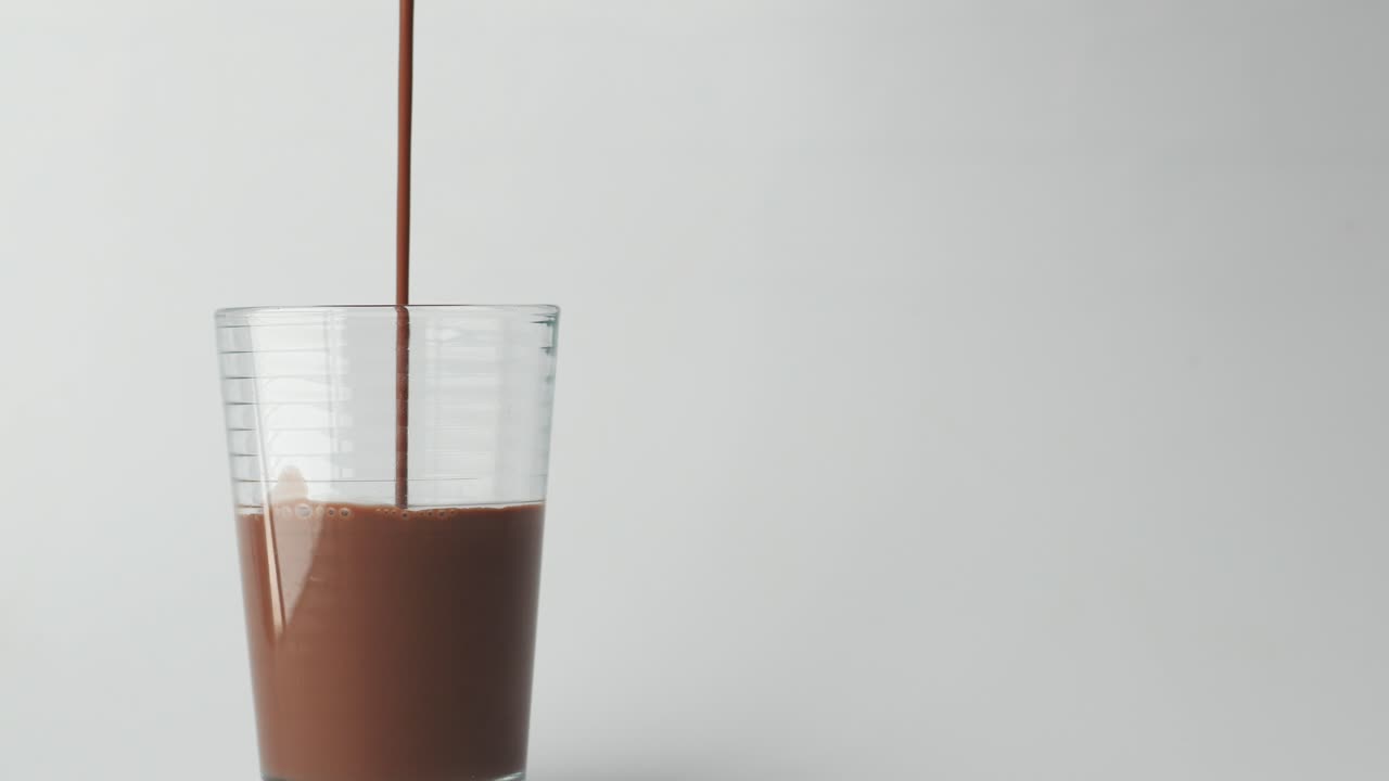 Versare latte al cioccolato in un bicchiere