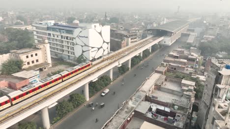 Aerial-View-Of-Orange-Line-Metro-Train-Approaching-Station-Near-McLeod-Road-In-Lahore-On-Elevated-Track