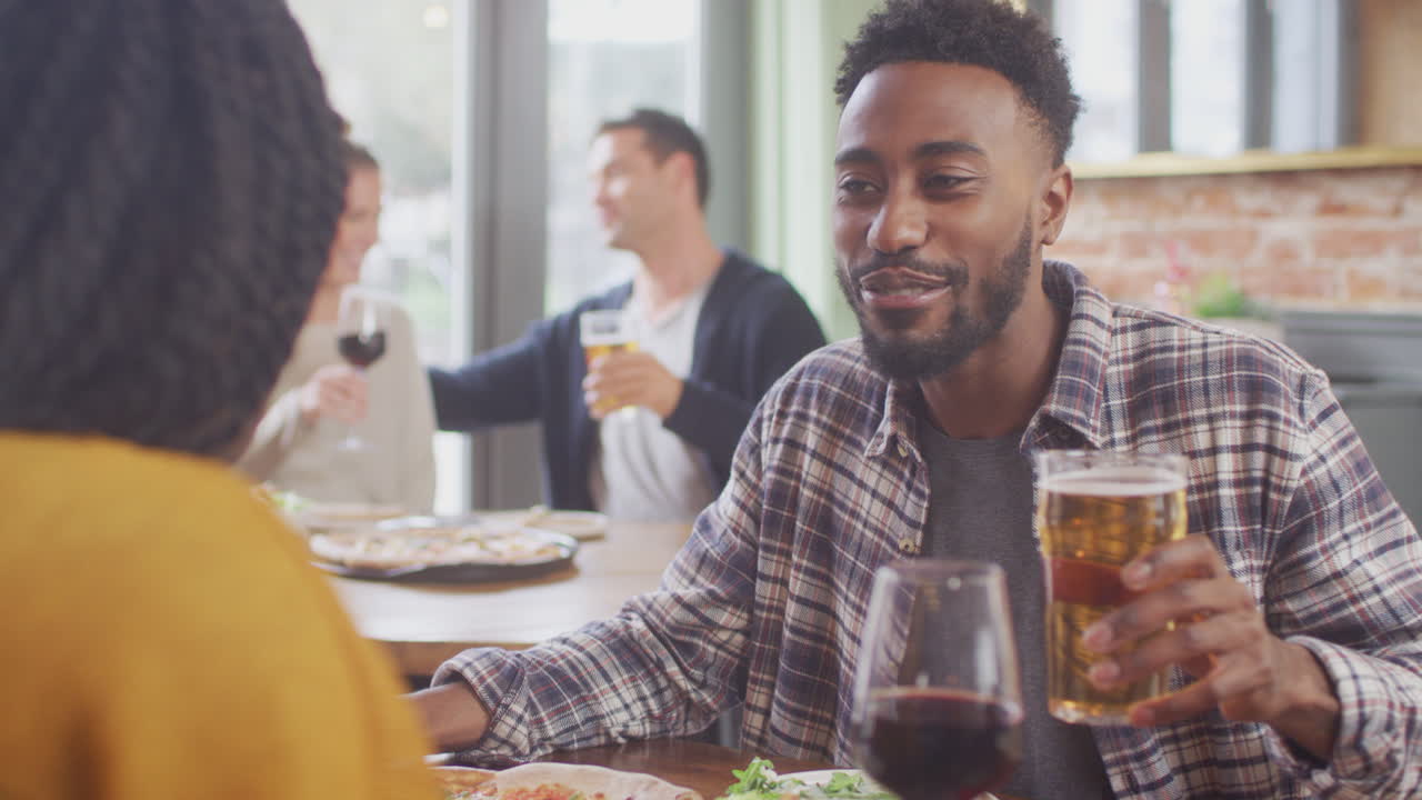 Smiling Young Couple On Date Enjoying Pizza In Restaurant Together Making A Toast