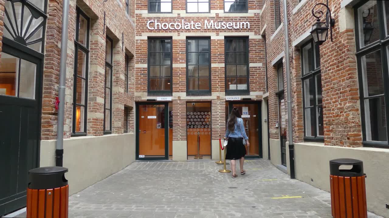 chica caminando hacia la entrada de un museo del chocolate en bruselas, bélgica