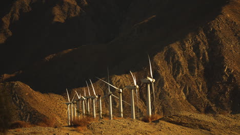 turbinas eólicas en miniatura que giran en un parque eólico en el desierto con una enorme montaña en el fondo cerca de palm springs en el desierto de mojave, california, ee.uu.