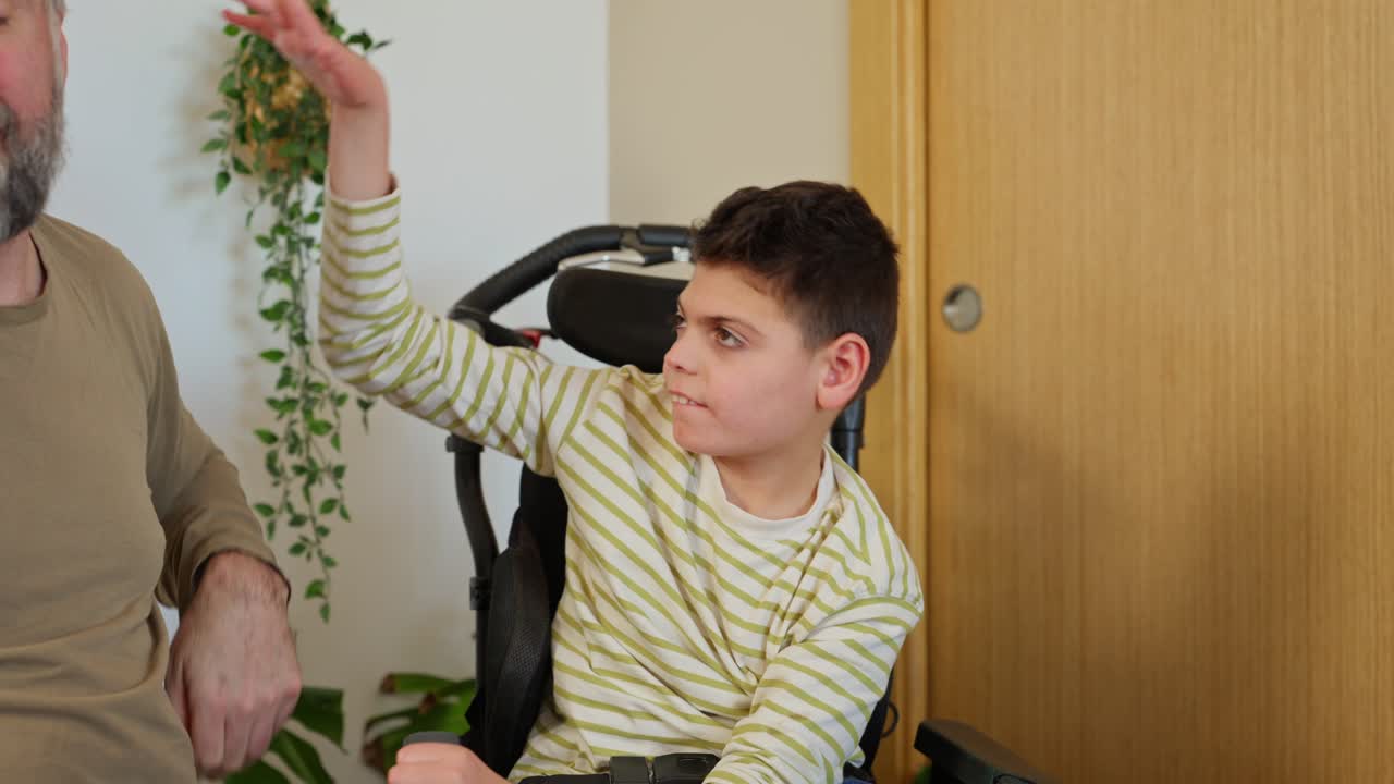 Caring Father Interacts Playfully with his Disabled Son in Wheelchair