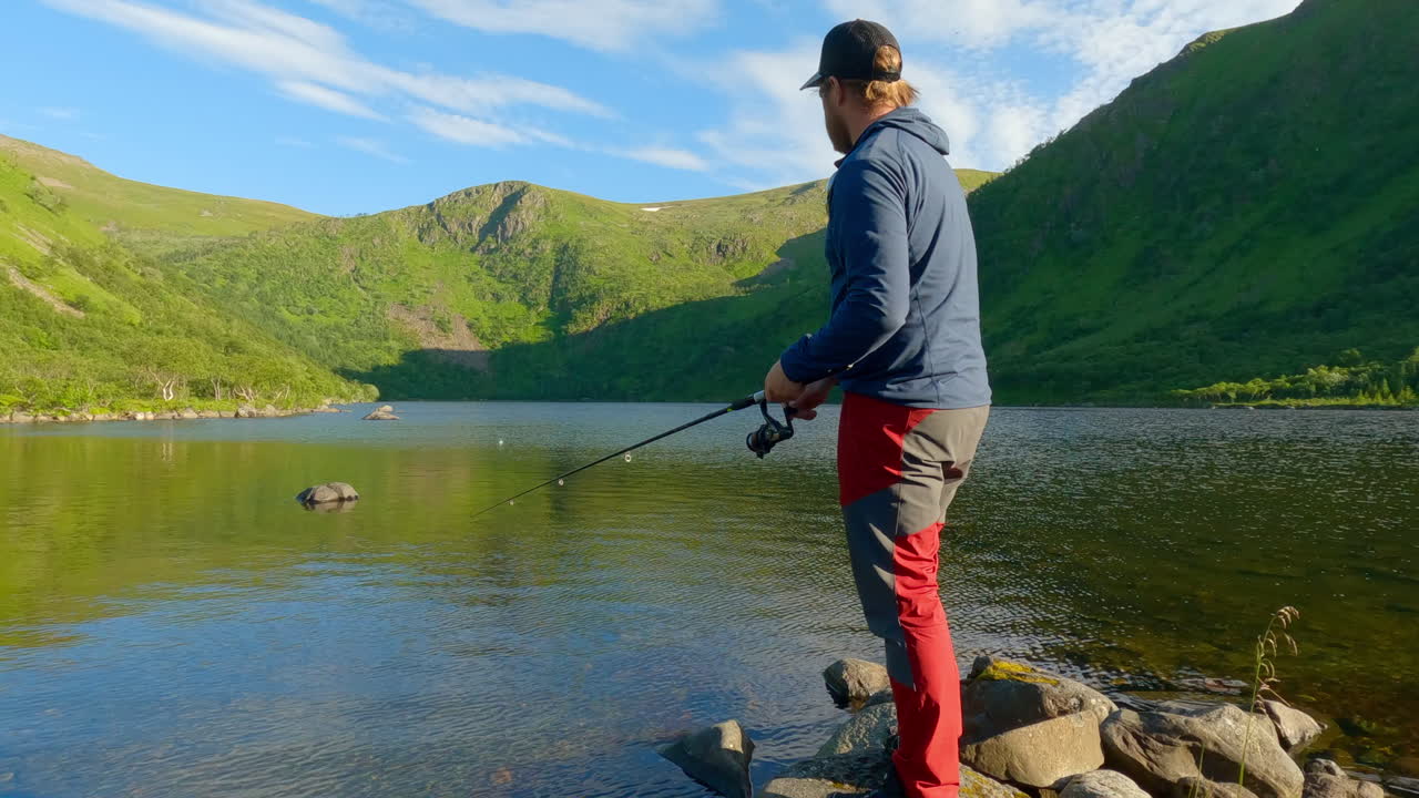 shot of a man fishing over the lake in the summer at Vesteralen Andoya, Norway