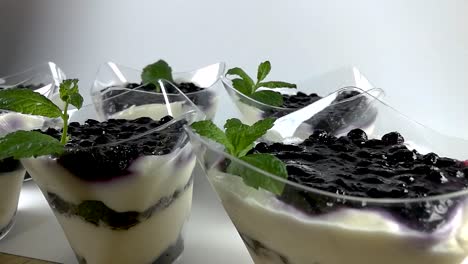 Male-hand-decorating-blueberry-cheesecake-in-a-small-plastic-cup-with-mint-leaves,-STILL