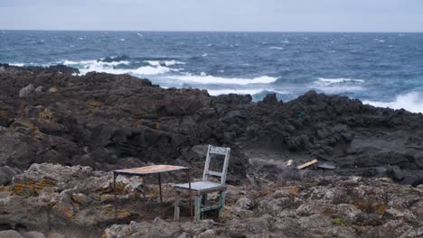 abandoned rustic furniture on rocky coastal path with ocean backdrop