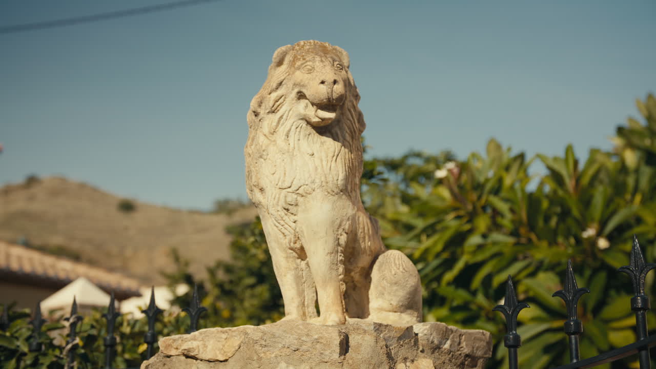 Close-up of aged lion sculpture in sunlit garden, symbolizing strength and protection, with soft background blur and warm light