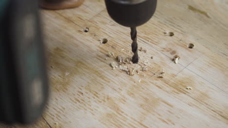 close up detail of power drill bit drilling into a wooden plank for diy skateboard