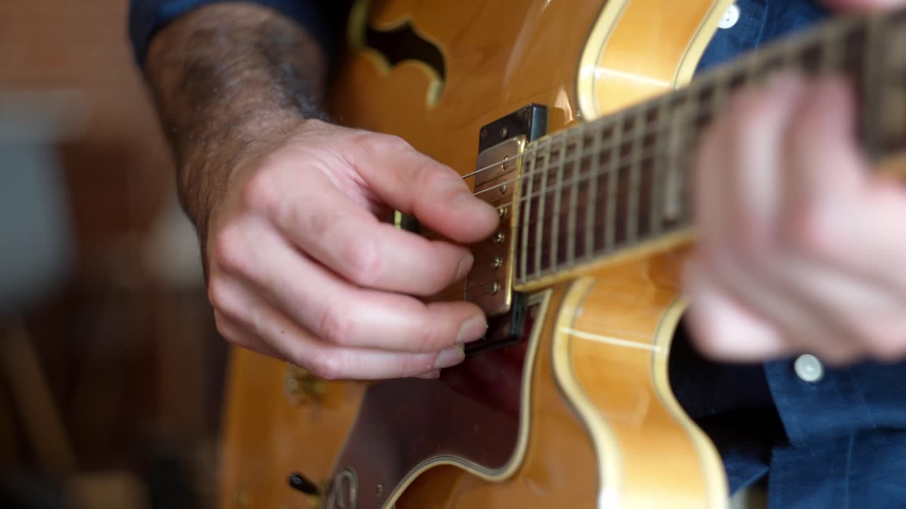 Unique view of a guitarist playing complicated melodies notes in an expensive electric guitar
