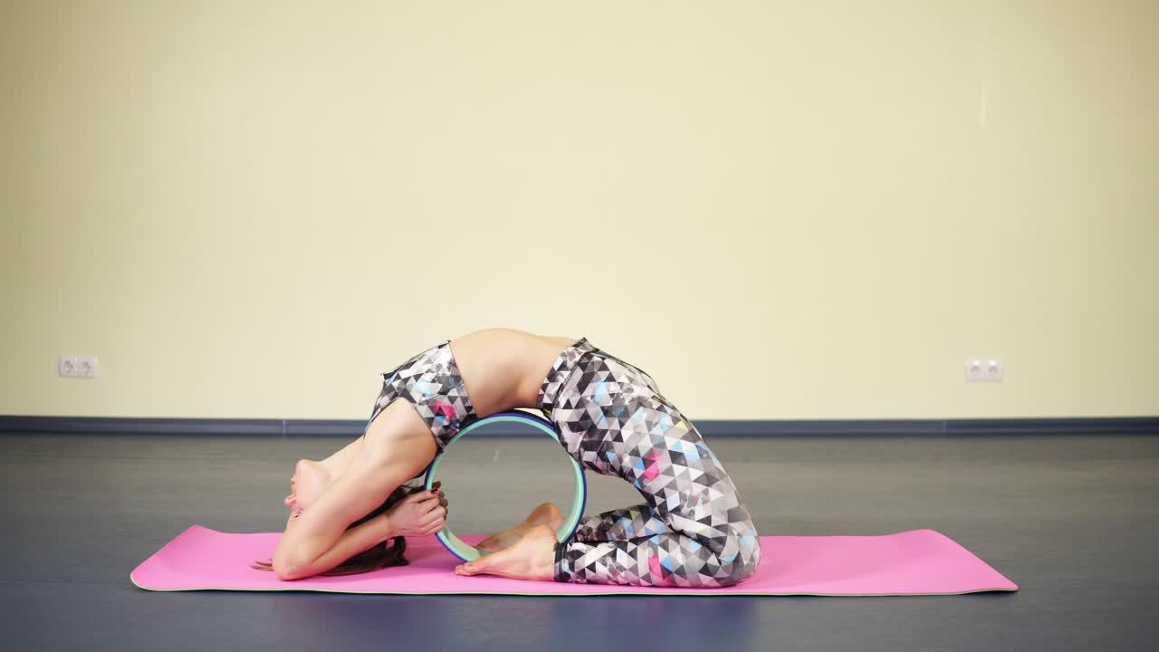 mujer con ropa deportiva atractiva que estira el torso y la espalda mientras practica asanas de yoga.