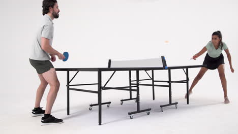 playing table tennis, man and woman competing in intense match indoors