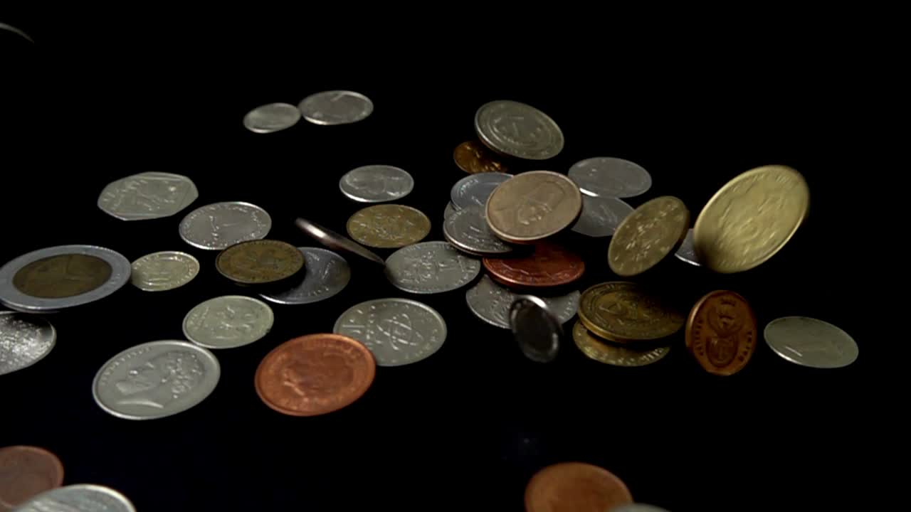 Coins fall on a black background. Slow motion