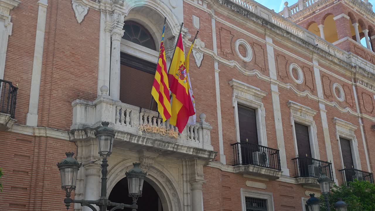 Vibrantes estandartes nacionales amarillos y rojos ondean fuera de la histórica fachada de ladrillo y piedra de la residencia episcopal barroca en el corazón de la ciudad vieja.