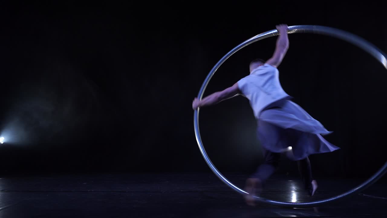 Artista della Ruota di Cyr esegue acrobazie su un palco nero con fumo