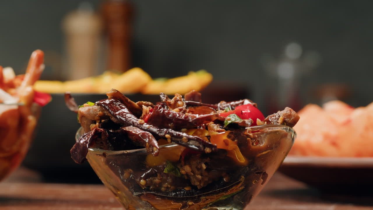 Taking a little bit of fermented eggplants with spices and mustard by chopstick close-up. Preservation of vegetables in glass jars. Fermentation preserved aubergine with greens.
