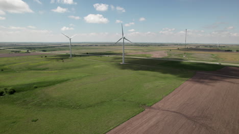 Turbinen-Drehen-Sich-Langsam-Im-Wind,-Während-Der-Verkehr-Auf-Der-Luftkurve-Der-Staatsstraße-Fährt