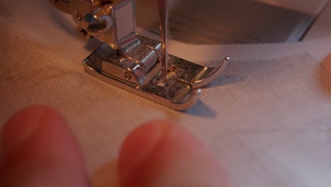 vista superior de la aguja y el pie de la máquina de coser moviéndose lentamente a través de la tela