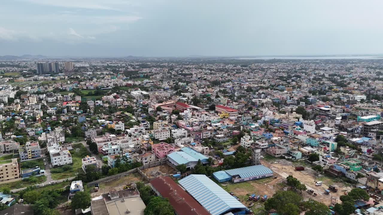 A sweeping aerial view shows the urban sprawl of Kattupakkam, Chennai, with the expansive waters of Chembarambakkam Lake stretching out in the distant background
