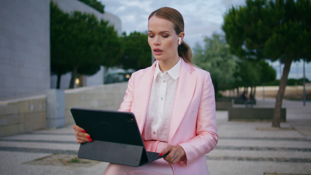 Girl freelancer listening webinar sitting city embankment with tablet close up.